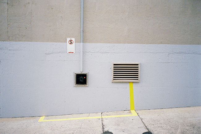 Image of a wall with a non stopping sign and an electric unit and a yellow line that defines a non stopping zone around it.