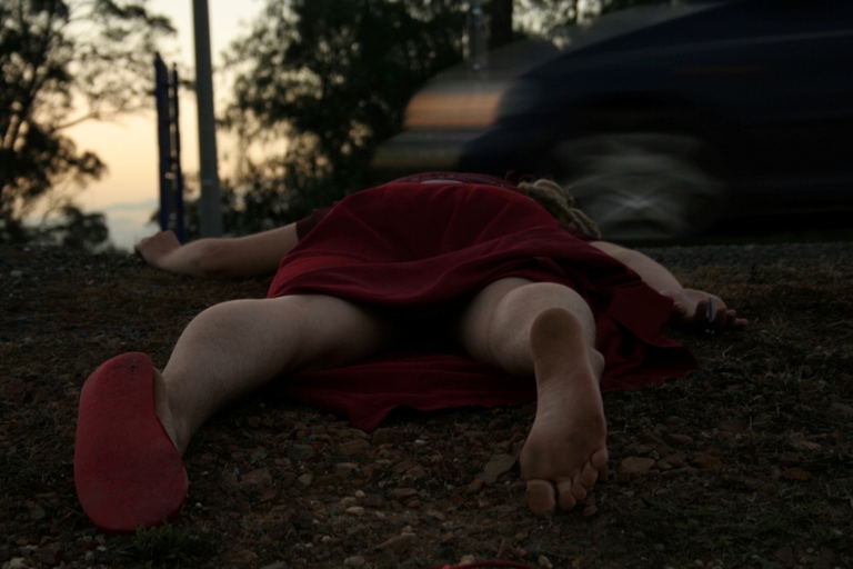 A woman's body lies by the side of a road