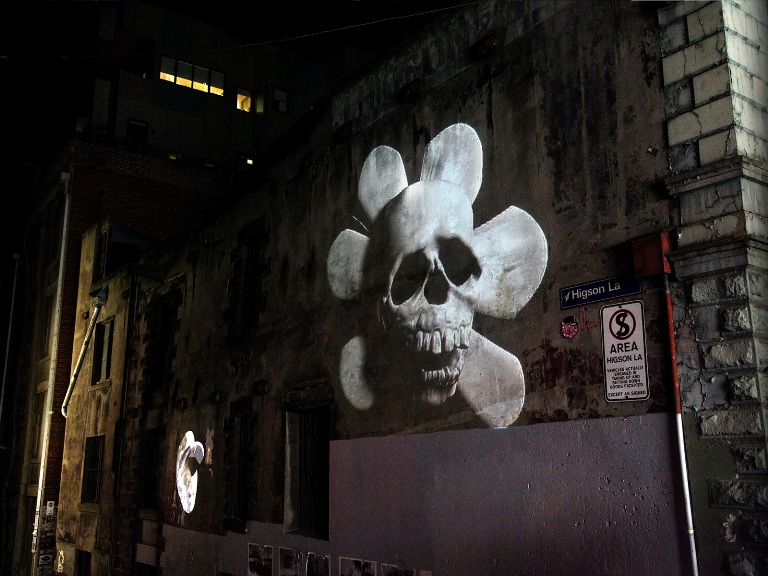 A photoraph of a skull pojected onto the side of a building